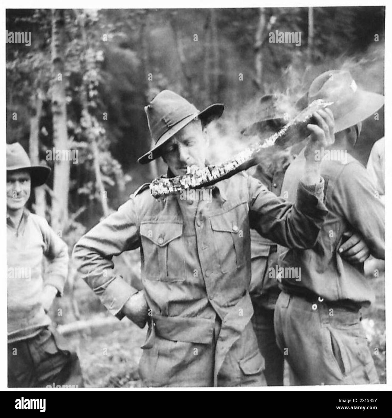 Rt. Ho. S.M. Bruce besucht australische Holzfäller in Schottland, wo anstelle eines Streichholzes von einem Arbeiter ein brennender Holzstamm verwendet wird. Stockfoto