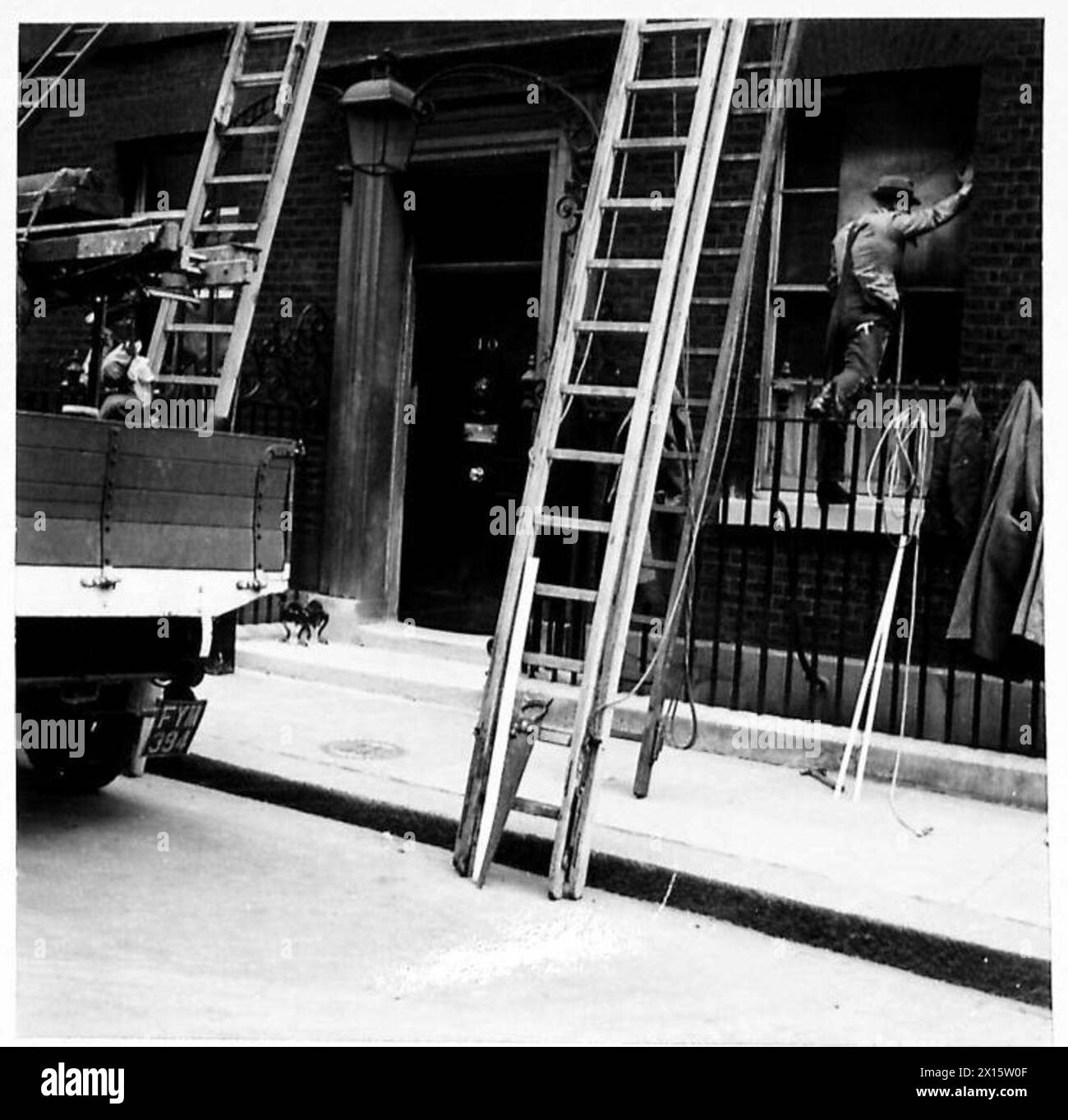 NO.10 DOWNING STREET WURDE WÄHREND DES RAID BESCHÄDIGT - eine geschäftige Szene in der Downing Street, als Arbeiter Leitern hochklettern, um die beschädigten Fenster in der No.10 British Army zu reparieren Stockfoto