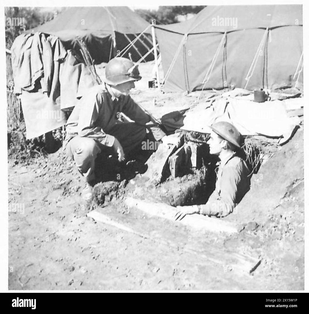 Der Privatmann Clarence Johnson von der 5. Armee spricht mit dem Privatmann Reg Tallant am Eingang zu einem ausgegrabenen Brückenkopf von Anzio. Die britische Armee ist anwesend. Stockfoto
