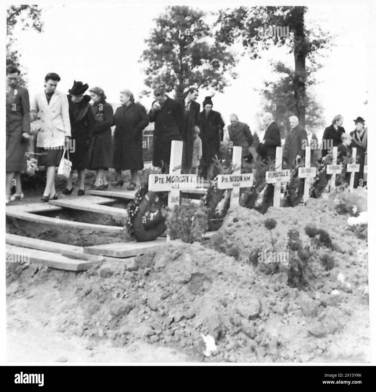 Zivilisten beobachten Gräber während der Beerdigung der abgestürzten Liberator-Opfer in Evere, British Army of the Rhine Presence. Stockfoto
