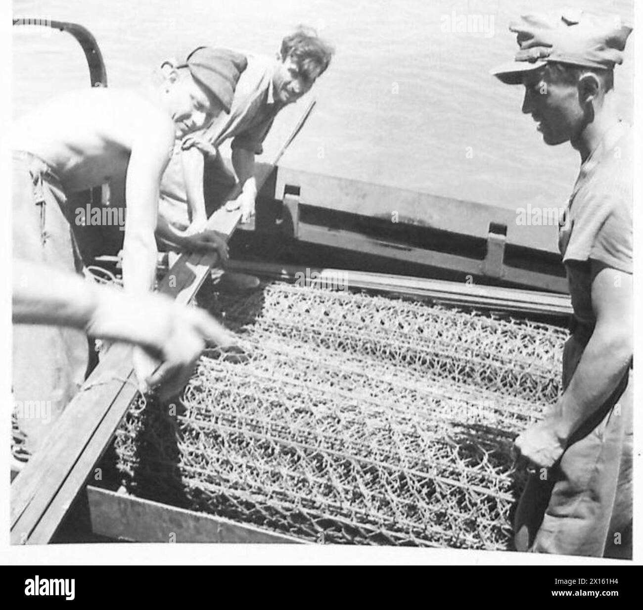 Italienische Gefangene helfen dabei, während der alliierten Invasion Siziliens Vorräte von einem Landeboot auf einen 1/2 Tonnen schweren amphibischen Lastwagen zu entladen, der logistische Unterstützungsoperationen der britischen Armee zeigt. Stockfoto