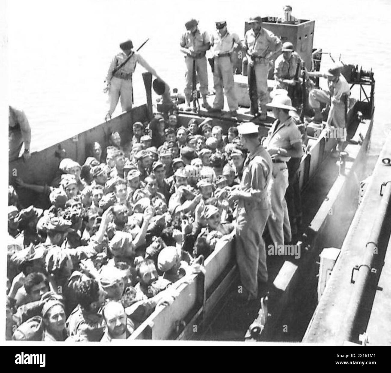 Sizilianische Gefangene steigen in Bizerta in Nordafrika aus und bitten einen amerikanischen Soldaten um Zigaretten, während das Boot am Dock entlang fährt. Stockfoto