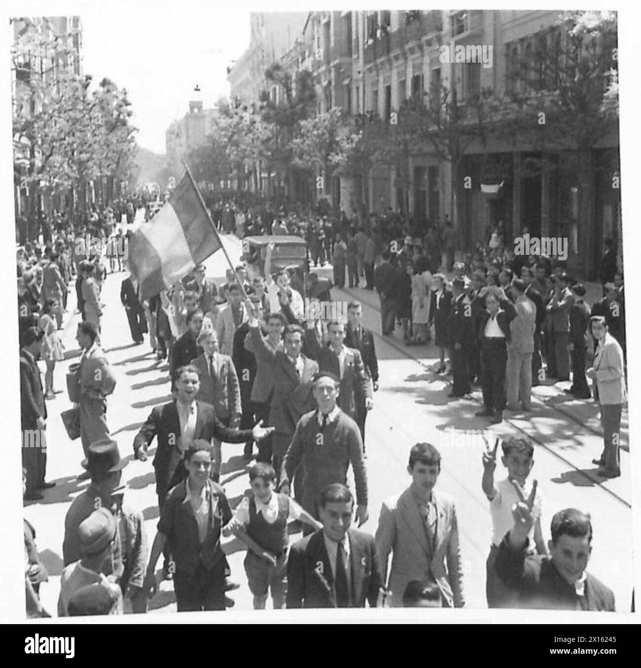 Britische Truppen dringen in Tunis ein, während einige der französischen Bevölkerung unter Aufsicht der britischen Armee ihre Nationalflagge durch die Straßen der Stadt ziehen. Stockfoto
