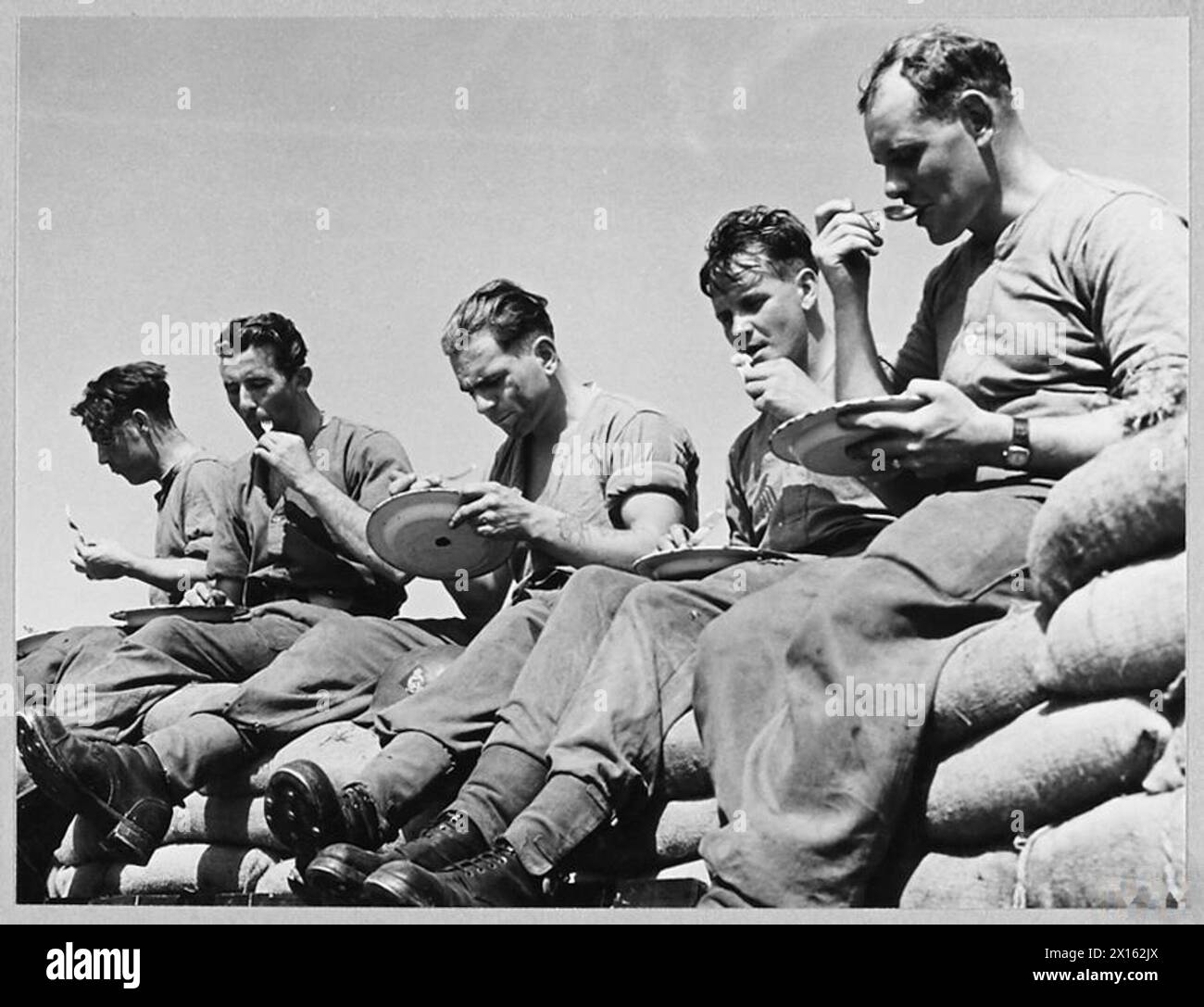 R.A.F. REGIMENT BEKÄMPFT DIE FLIEGENDE BOMBE - Bild (ausgestellt 1944) zeigt - Mahlzeiten werden ohne Zeremonie gegessen. Eine Crew isst auf der Waffenaufstellung - von links nach rechts -, führender Flugzeugbauer McKiernan aus Cavan, Irland; führender Flugzeugführer G.D. Spence of Derry City, N.Ireland; führender Luftfahrzeugführer J. Bebbington von Stoke; Corporal C.N. Evans von New Tredegar, Mon, und Sergeant J. Veach von der Coventry Royal Air Force Stockfoto