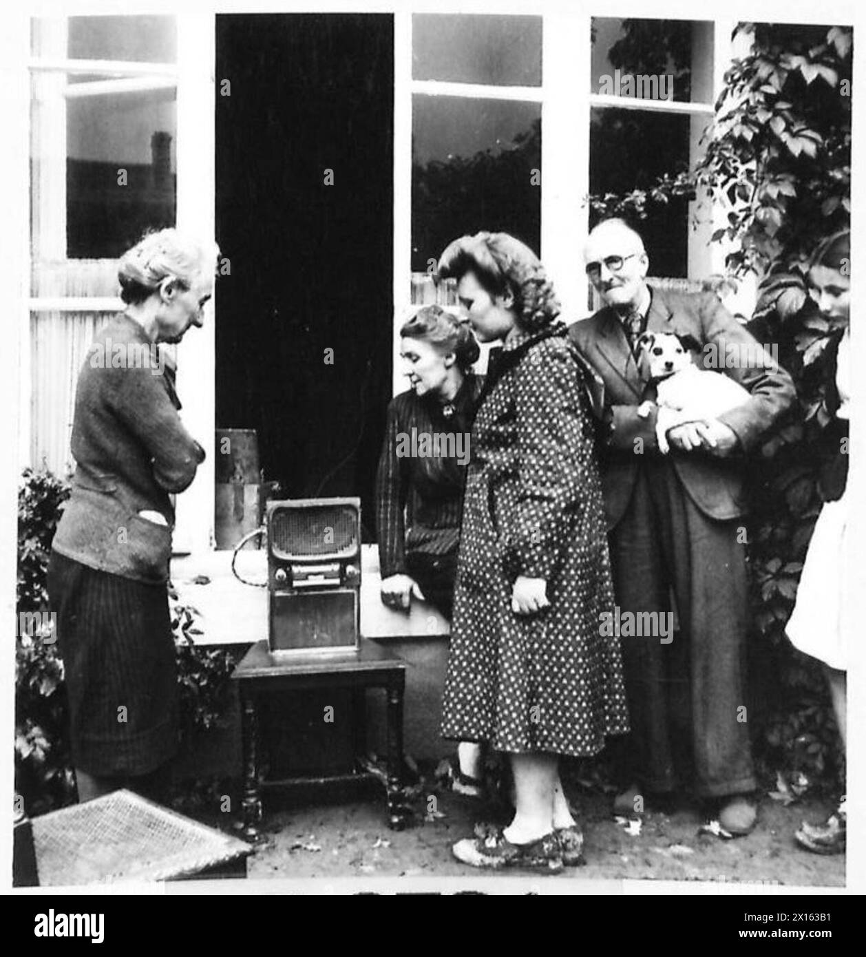 Die französischen Dorfbewohner in Cully hören das Funkgerät der englischen Soldaten und beobachten Reaktionen, während sie Nachrichten aus der Kriegszeit hören, darunter Pierre Lefevre. Stockfoto