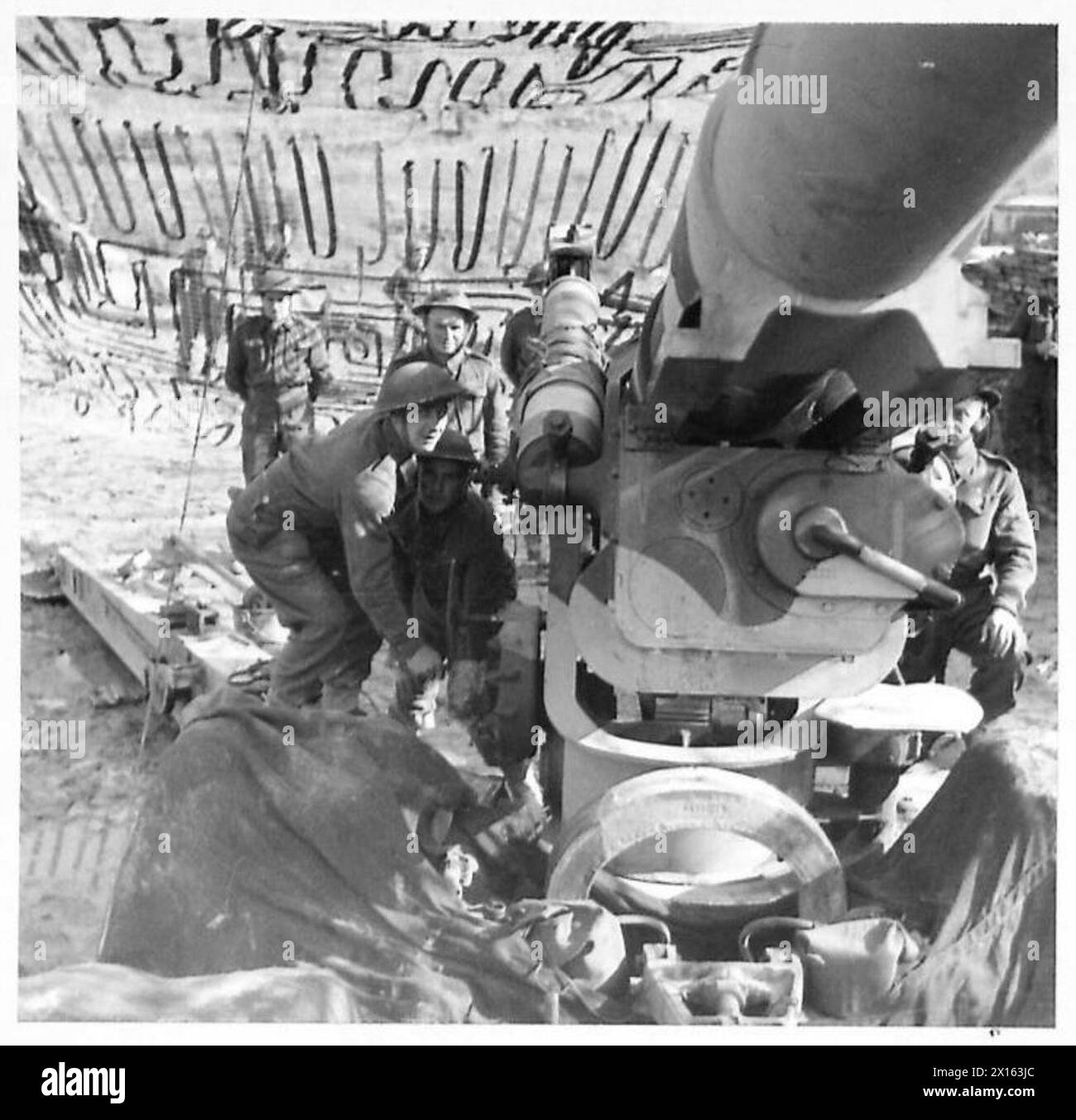 Gunner Bedeler of Leicester hebt eine Waffe an, während Gunner Johnson aus Collingham die Reichweite eines weiteren amerikanischen schweren Artilleriegebietes in Italien einstellt. Stockfoto