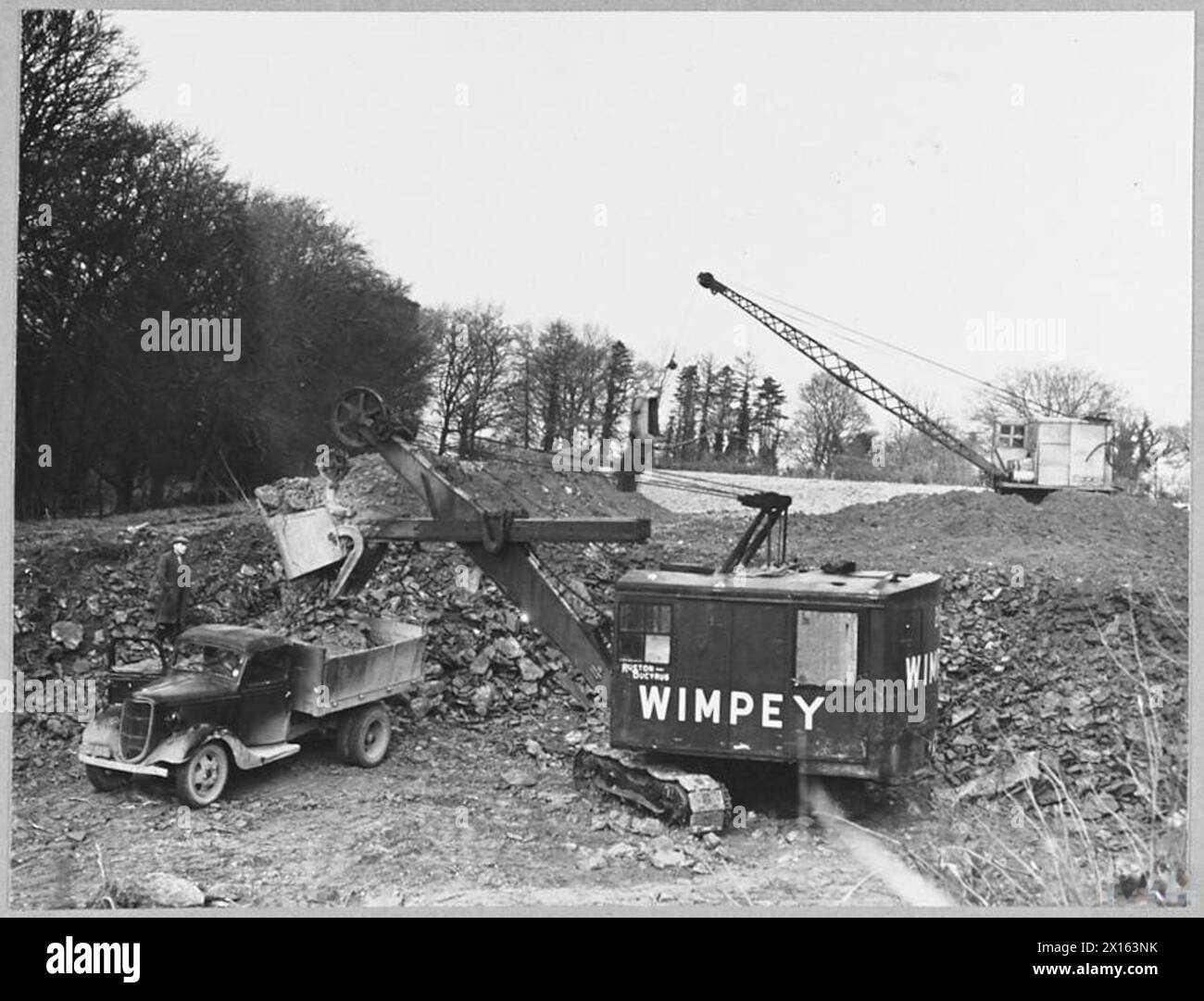 Ruston Bucyrus Construction Equipment wurde 1943 für den Bau von Flugplätzen verwendet, wobei Model 21 R.B. Steine in LKW verladen und Model 16 R.B. Oberboden unter Aufsicht des Ministeriums für Versorgung räumt. Stockfoto