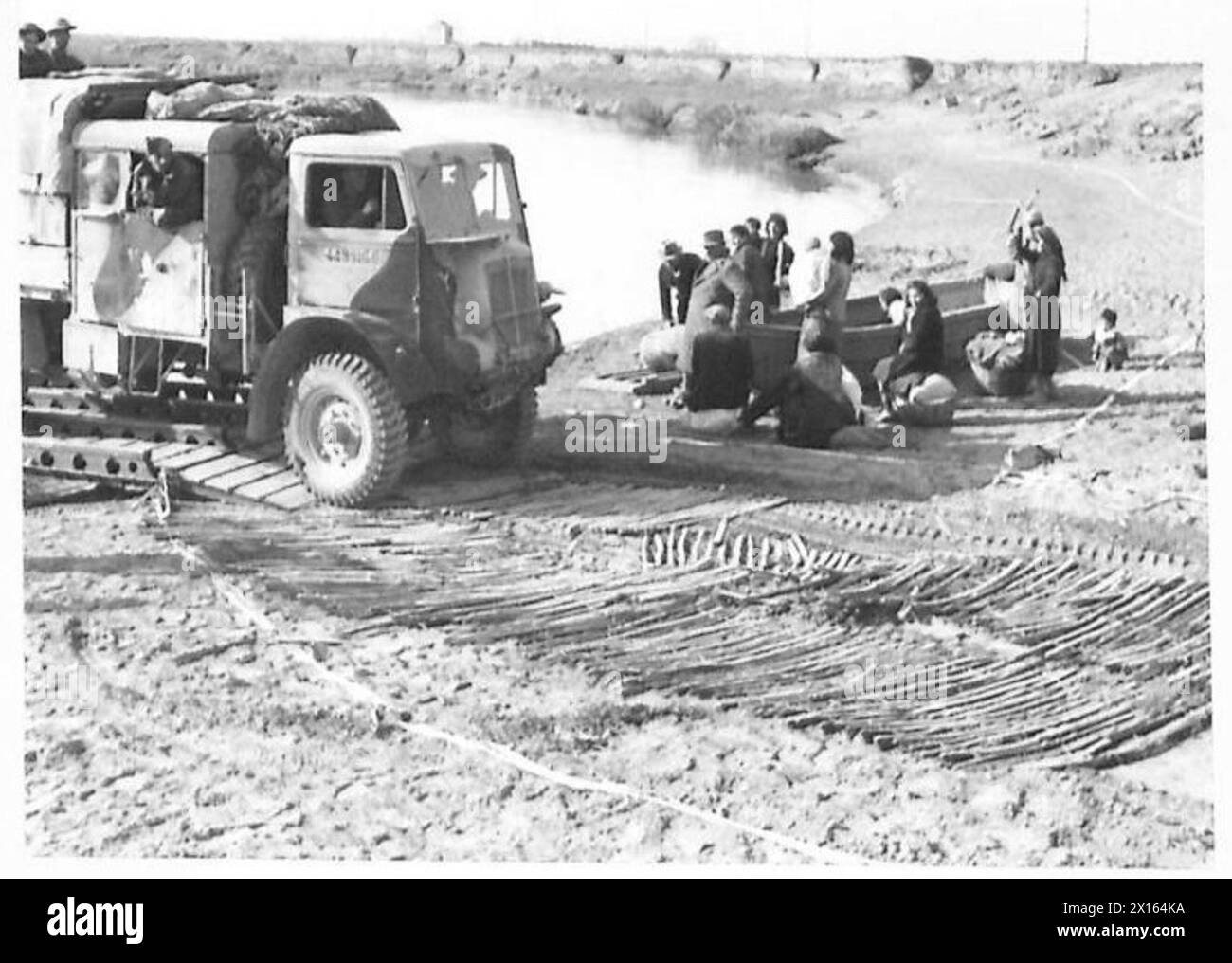 Ein Bofors-Schlepper überquert den Garigliano River auf einer Pontonbrücke, während eine Gruppe von Flüchtlingen auf die Überquerung zum Südufer wartet Stockfoto
