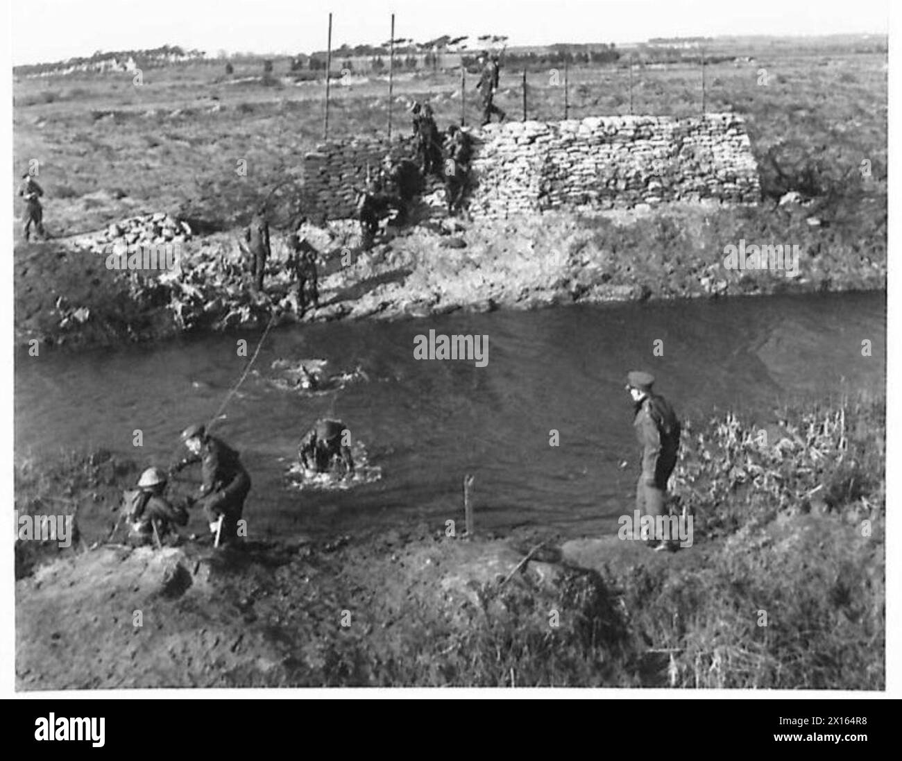 KAMPFSCHULAUSBILDUNG - nachdem sie sich drei Viertel Meilen verdoppelt haben, müssen die Schüler diesen Fluss überqueren. Ein Seil ist für Nichtschwimmer der British Army vorgesehen Stockfoto