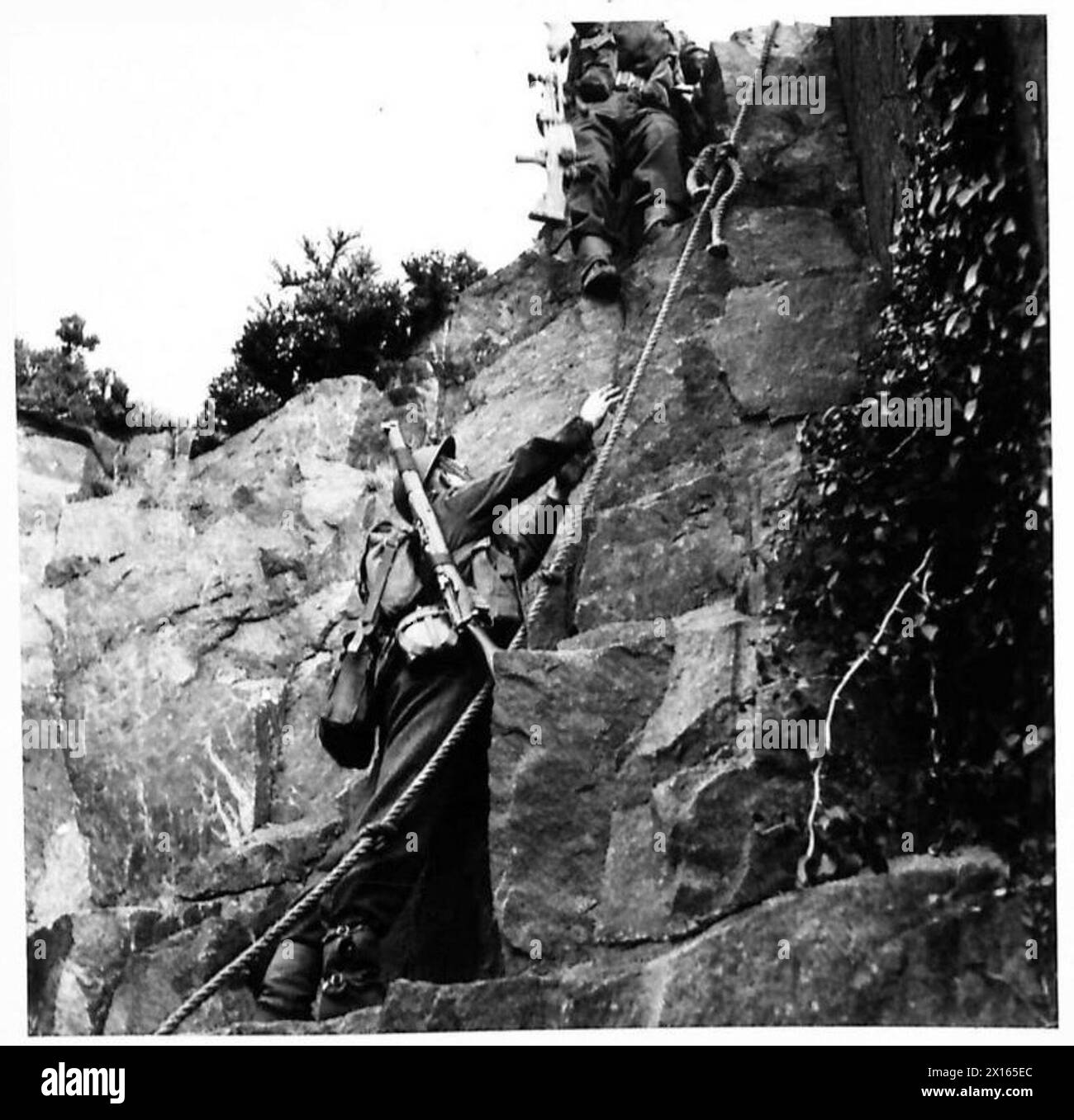 LANCASHIRE JUNGS HÄRTEN sich ab – der erste Mann, der die Klippen hinaufführt, legt ein Seil um einen Felsbrocken, sodass andere die Klippe erklimmen und den Kurs der British Army fortsetzen können Stockfoto