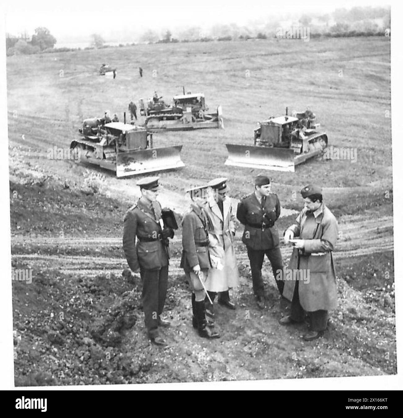 Kriegskorrespondenten werden mit Oberstleutnant T.C.W. Bowen nach einer Demonstration an der Army Tractor School während der Operationen der British Army fotografiert. Stockfoto