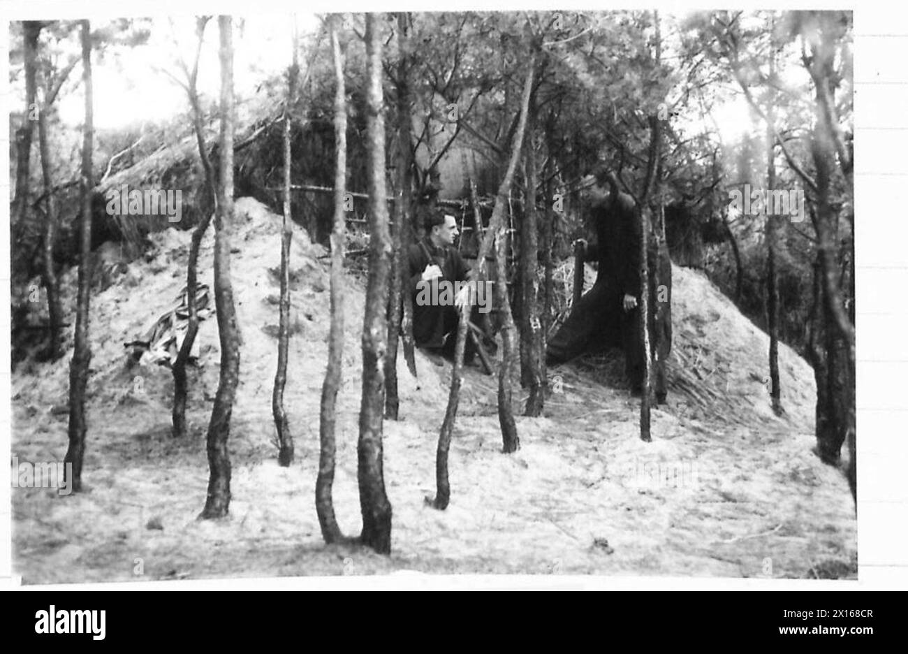 Ein Strohhaus in den Wäldern stellt einen Teil des niederländischen Widerstands P.A.N.-Lagers dar und weist minimale Strukturen in der Waldlandschaft auf. Stockfoto
