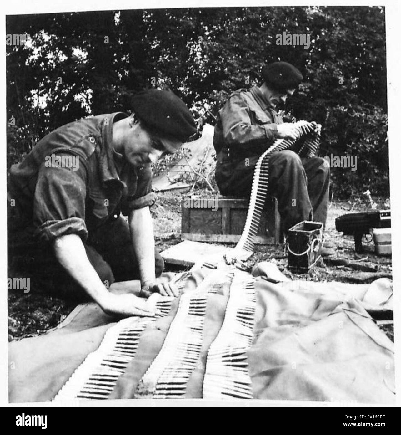 Eine Churchill-Panzerbesatzung führt Wartungsarbeiten durch, überprüft Munitionsgurte und reinigt das 7,92-mm-Maschinengewehr Besa, um die Kampfbereitschaft zu gewährleisten. Stockfoto