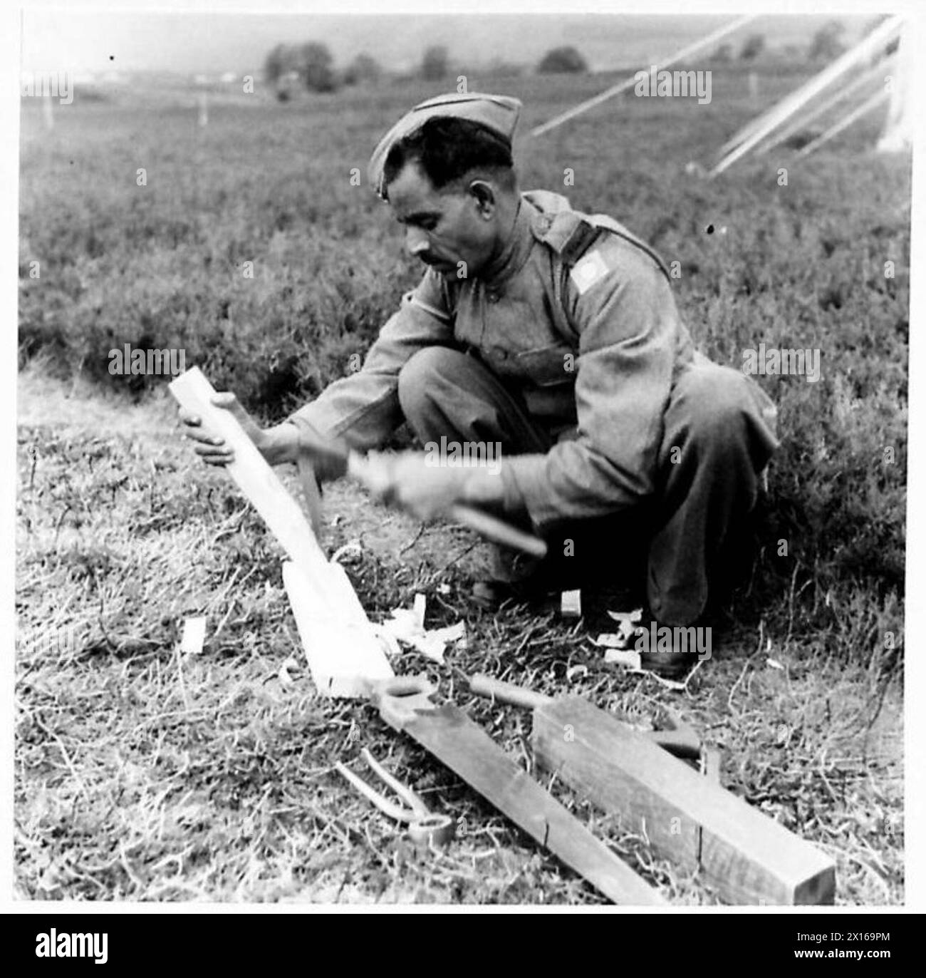 Ein Zimmermann, der dem Royal Indian Army Service Corps (RIASC) angehört, führt Arbeiten in einem Lager durch und wartet Strukturen und Ausrüstung. Stockfoto