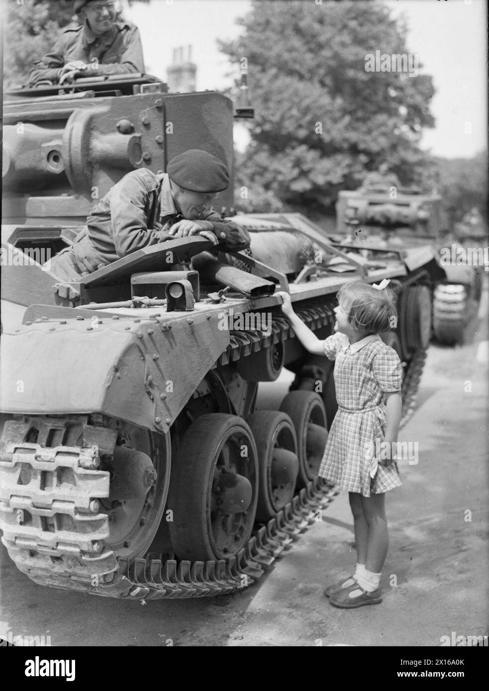 DIE BRITISCHE ARMEE IM VEREINIGTEN KÖNIGREICH 1939-1945 – Trooper Bill Blackett, Fahrer eines Valentine-Panzers der 29. Panzerbrigade, 11. Panzerdivision, unterhält sich am 25. Juni 1942 mit Pat Brooker, 5 Jahre alt, während eines Zwischenstopps im Dorf Rottingdean in Sussex Stockfoto