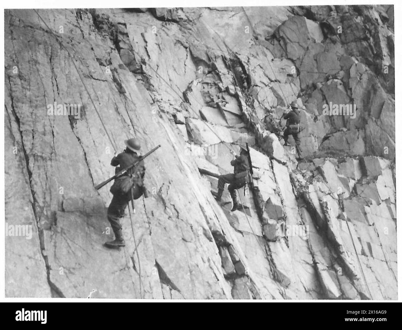 DER KÖNIG BEOBACHTET LANDUNGSÜBUNGEN - Truppen, die während der Übungen eine felsige Klippe kalken, britische Armee Stockfoto