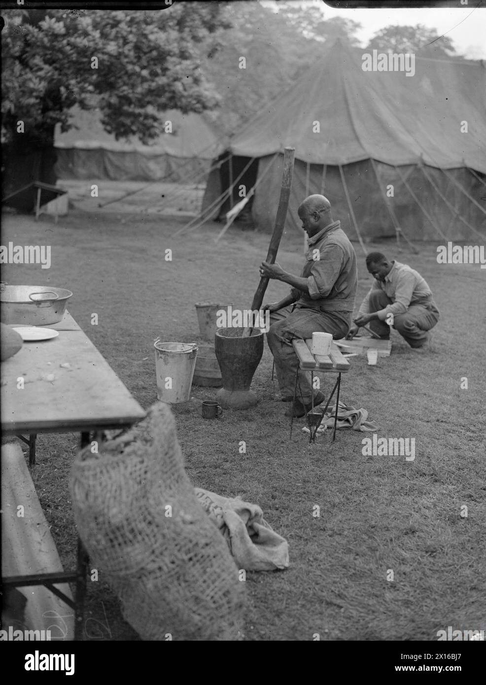 VICTORY MARCHERS CAMP IN LONDON: UNTERKUNFT IN KENSINGTON GARDENS, LONDON, ENGLAND, Großbritannien, 1946 - Ein westafrikanischer Koch bereitet vor dem Zeltlager in Kensington Gardens, London, eine Mahlzeit zu. Männer mehrerer afrikanischer Regimenter gehören zu Tausenden von Truppen aus dem ganzen Reich, die an der Siegesparade teilnehmen werden Stockfoto