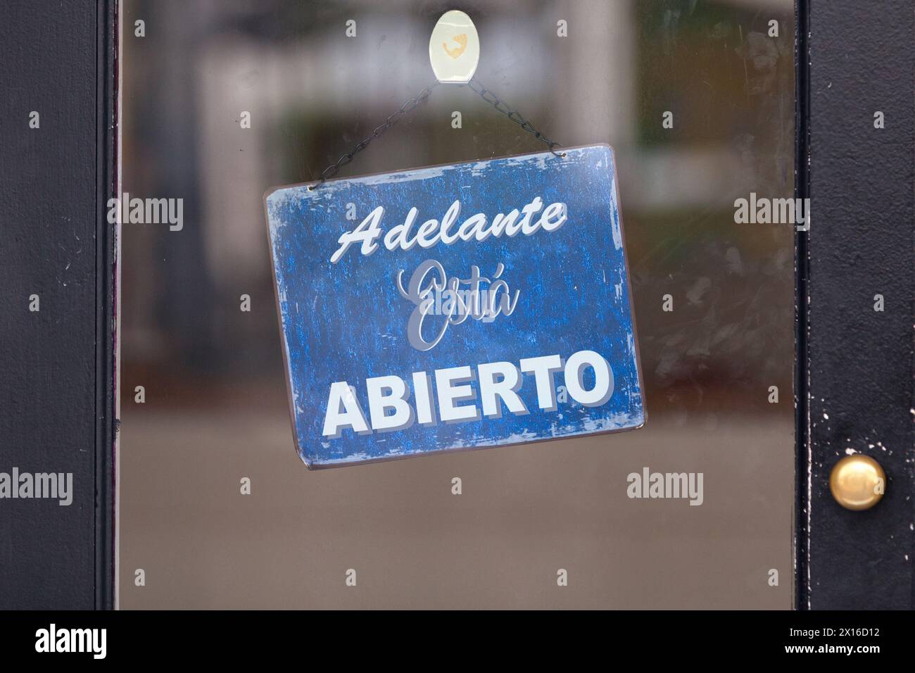 Offenes Schild mit der spanischen Schrift „Adelante, está abierto“, was im Englischen „Kommen Sie, es ist offen“ bedeutet. Stockfoto