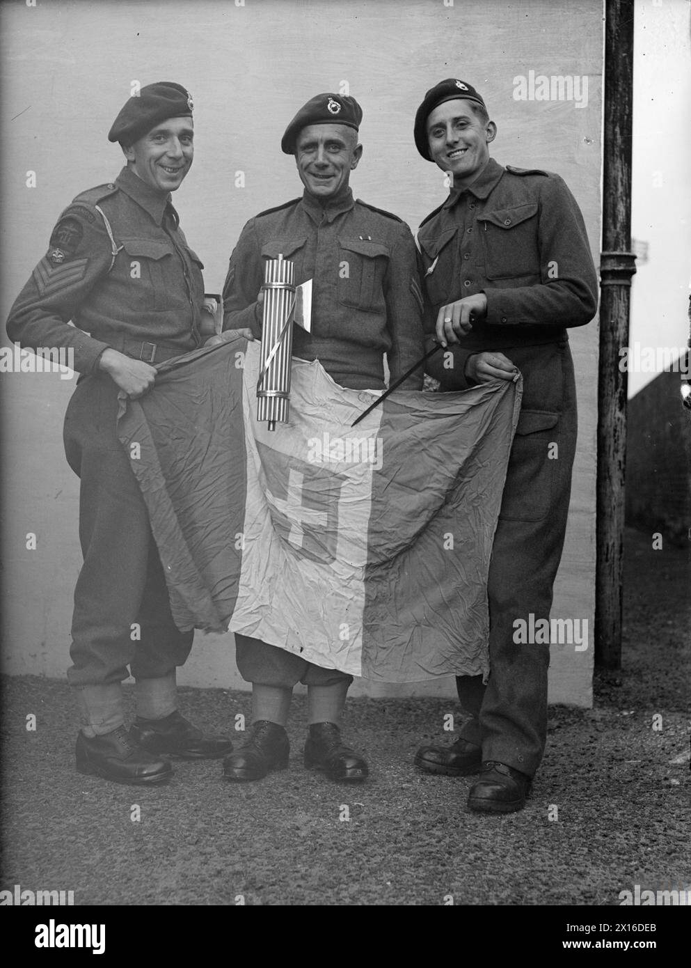 ROYAL MARINES, DIE IN SALERNO GEKÄMPFT HABEN. 5. JANUAR 1943, ROYAL MARINE DEPOT, DEAL, KENT. - Colour Sgt J Fulton aus Glasgow; Corporal W S Houghton aus Lincoln und Corporal M C Allen aus Norwich mit gefangener faschistischer Flagge und Boyonetten Stockfoto