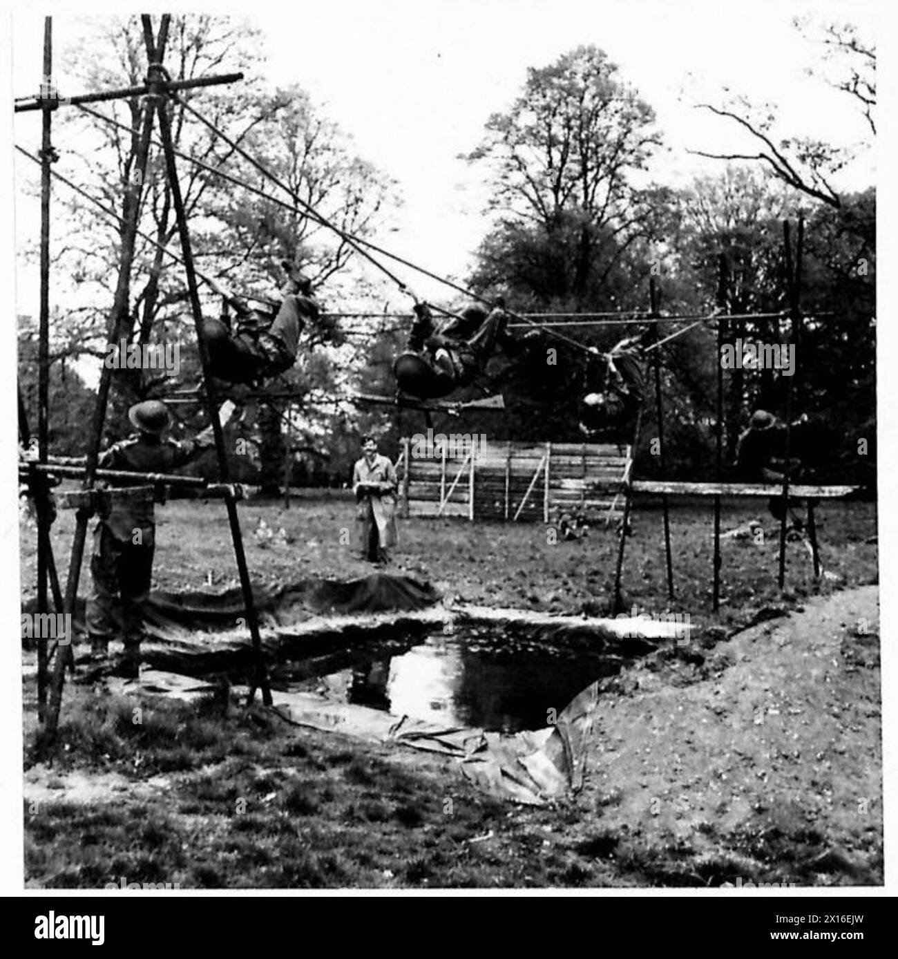 Die Teilnehmer überqueren eine Seilbrücke in einem Team-Angriffskurs während eines militärischen Waffen- und Sporttreffens unter Aufsicht der British Army. Stockfoto