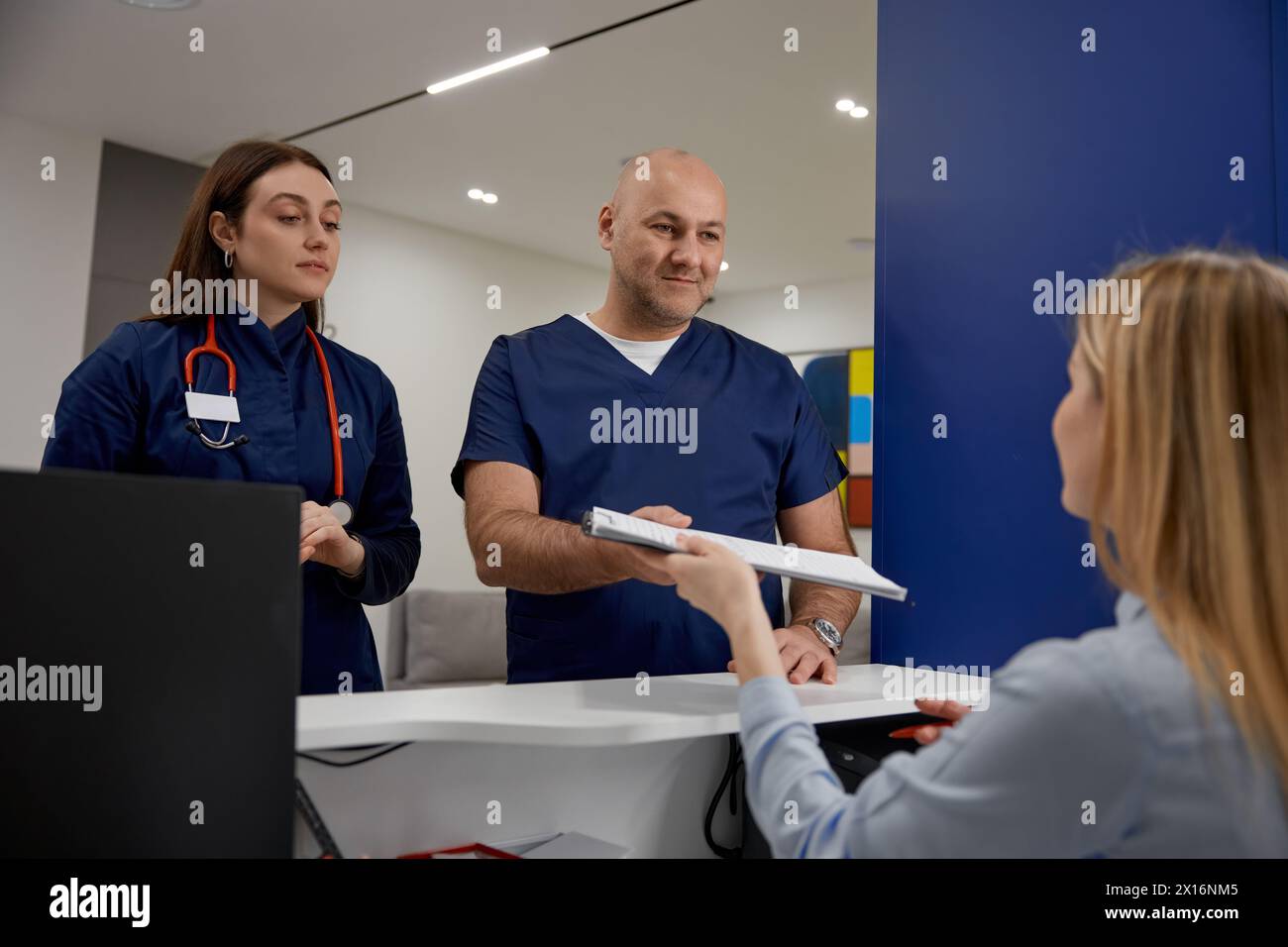 Männliche und weibliche Ärzte überprüfen den Zeitplan in der Nähe der Rezeption Stockfoto