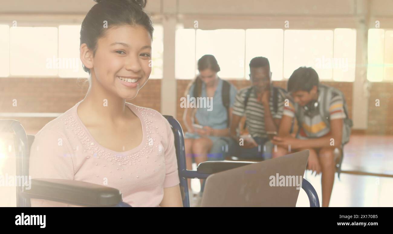 Bild von Lichtern über glücklichen behinderten birassischen Schülerinnen, die in der Schule Laptop benutzen Stockfoto