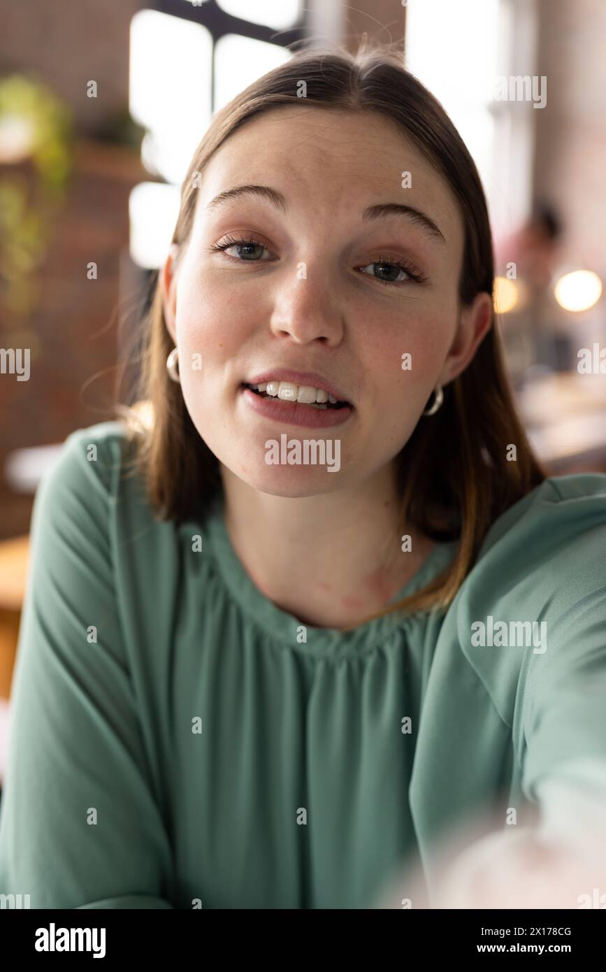 Kaukasische junge Profi, die bei Videogesprächen in die Kamera schaut, mit grünem Oberteil Stockfoto