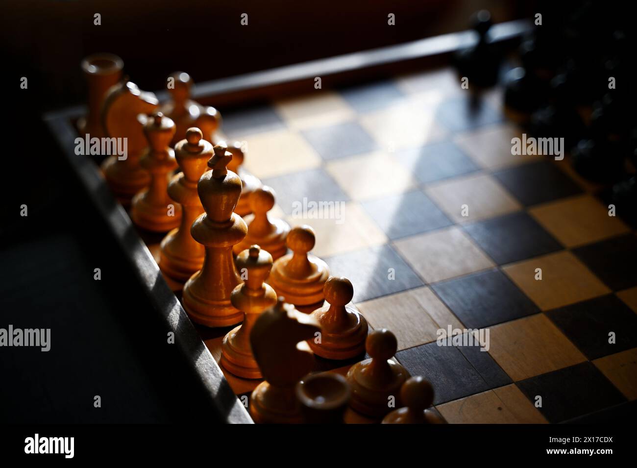 Hölzerne Schachfiguren auf einem alten Brett in der Sonne Stockfoto
