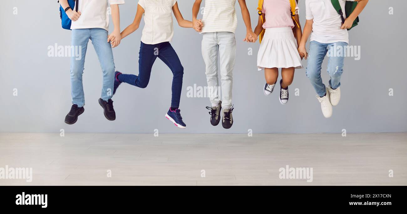 Beine von Schülerkindern, die Hände auf grauem Hintergrund halten. Stockfoto