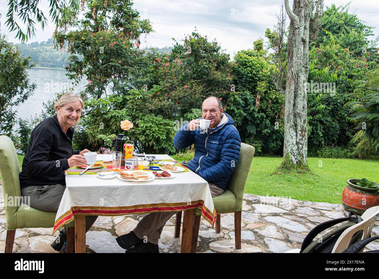 Ein Paar frühstückt bequem in den Gärten des Hotels, das sich mitten im See Bunyonyi im Süden Ugandas befindet Stockfoto