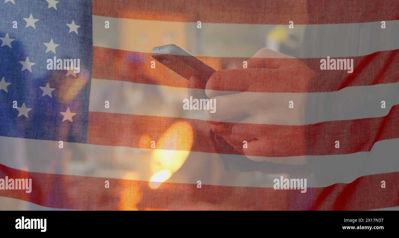 Bild einer amerikanischen Flagge, die über den Menschen winkt, indem sie das Telefon im Hintergrund benutzt Stockfoto