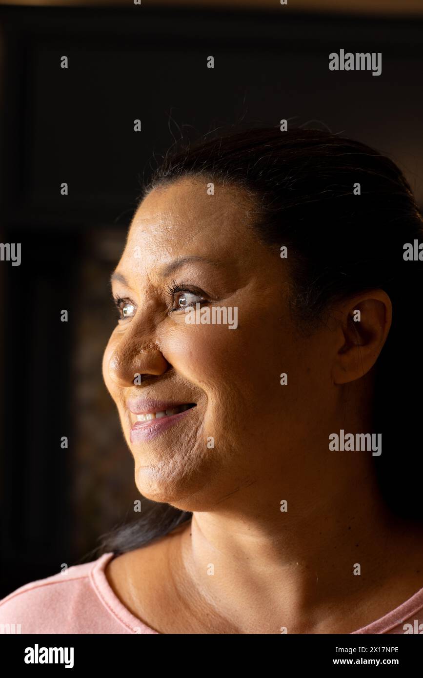 Reife Frau, die wegschaut und zu Hause ein pinkfarbenes Oberteil trägt Stockfoto