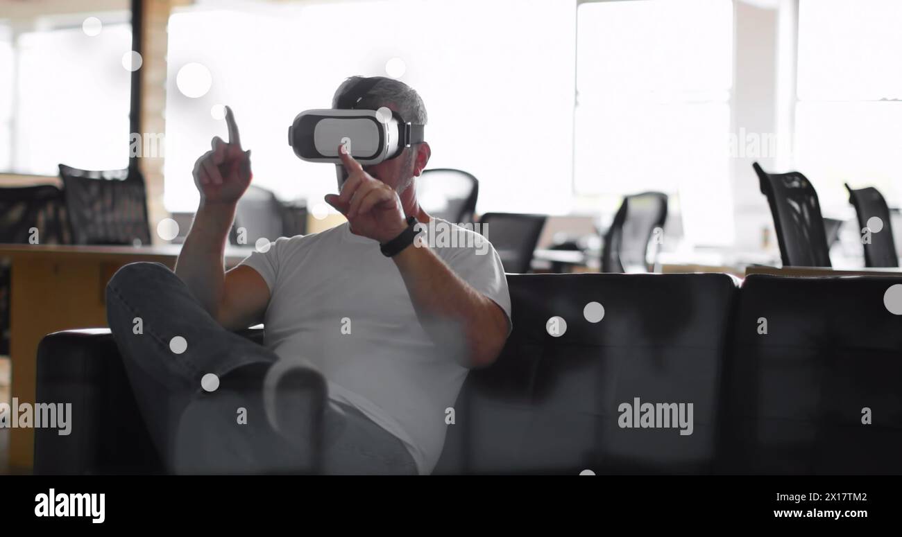 Bild von Flecken über einem kaukasischen Geschäftsmann mit vr-Headset im Büro Stockfoto