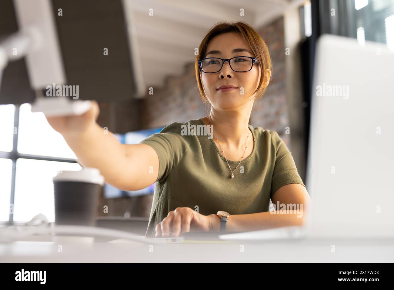 Asiatischer, ausgereifter, professioneller Computermonitor, der sich auf die Arbeit in einem modernen Geschäftsbüro konzentriert Stockfoto