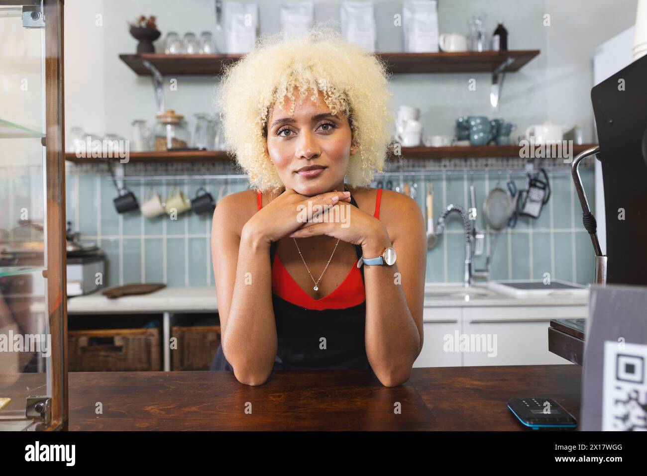 Birassischer Barista mit lockigen blonden Haaren, das Kinn auf den Händen aufliegt Stockfoto