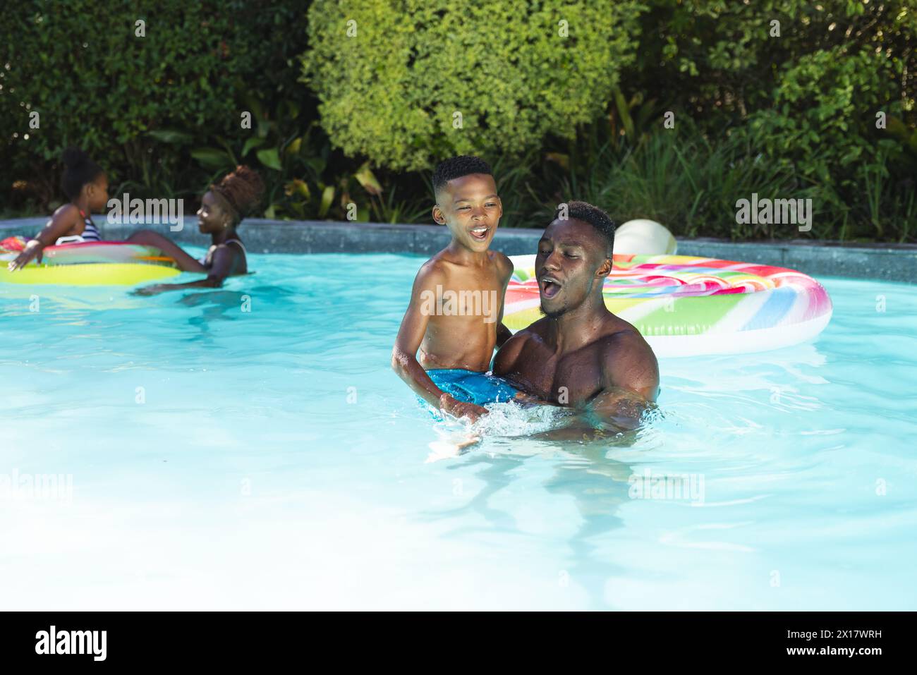 Afroamerikanischer Vater und Sohn genießen das Schwimmen im Pool zu Hause mit Kopierraum Stockfoto