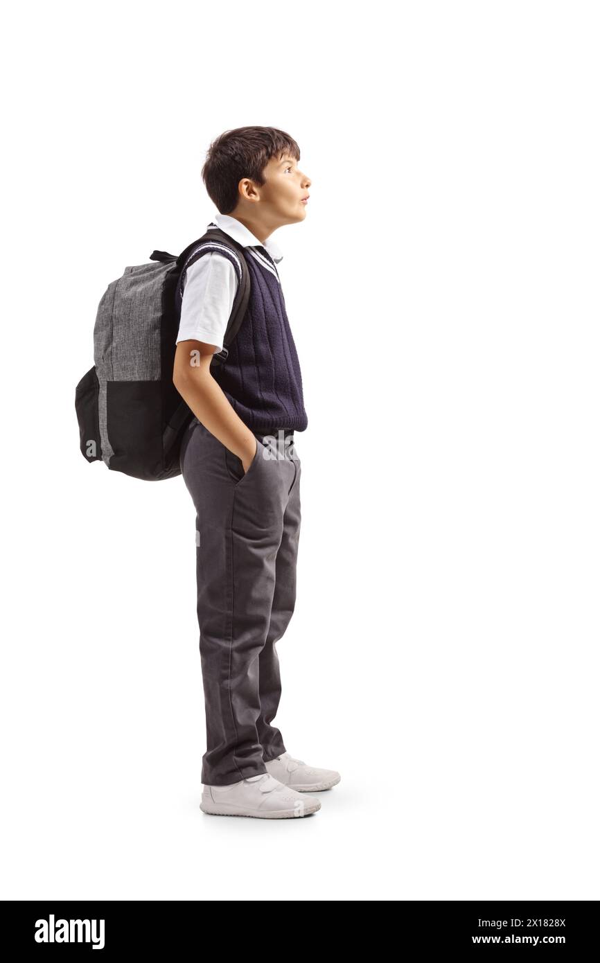 Profilaufnahme eines Schuljungen in Uniform, der mit Händen in Taschen steht und isoliert auf weißem Hintergrund aufblickt Stockfoto