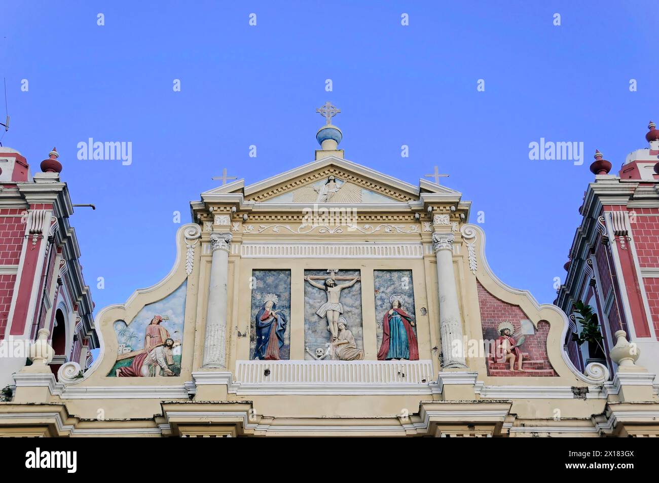 Kirche El Calvario, Leon, Nicaragua, barocke Kirchenfassade mit religiösen Skulpturen und einem Kruzifix vor einem blauen Himmel, Nocaragua, Central Stockfoto