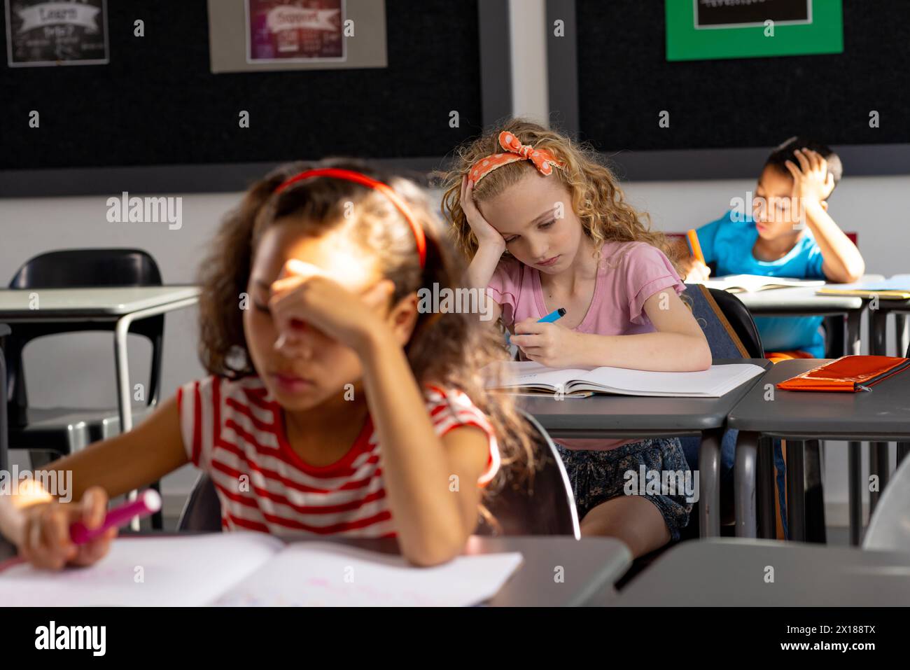 In der Schule konzentrieren sich verschiedene junge Schüler auf ihre Arbeit im Klassenzimmer Stockfoto