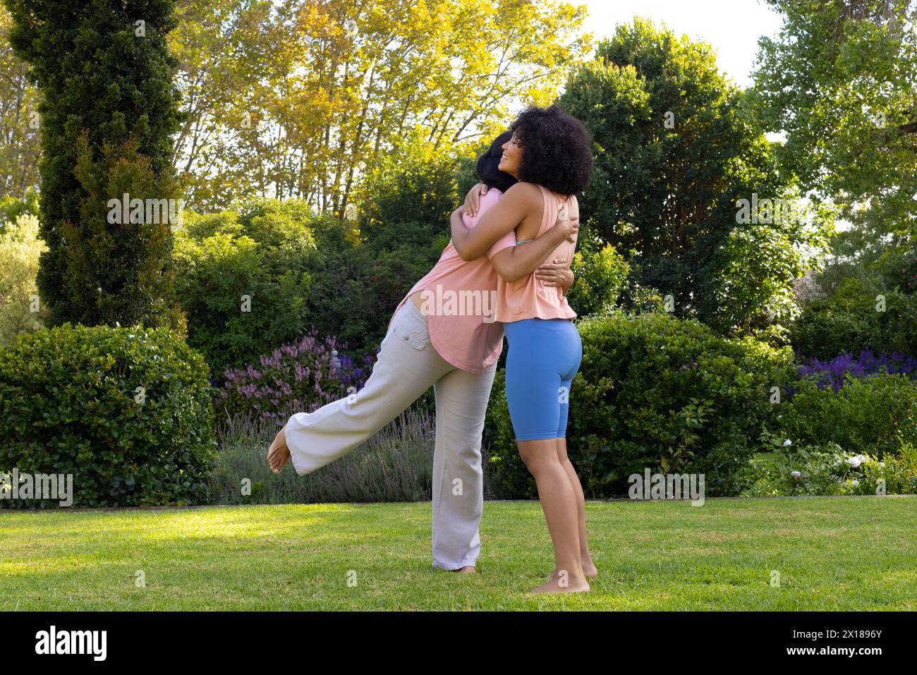 Reife Frau, die eine Erwachsene Tochter im Garten umarmt Stockfoto
