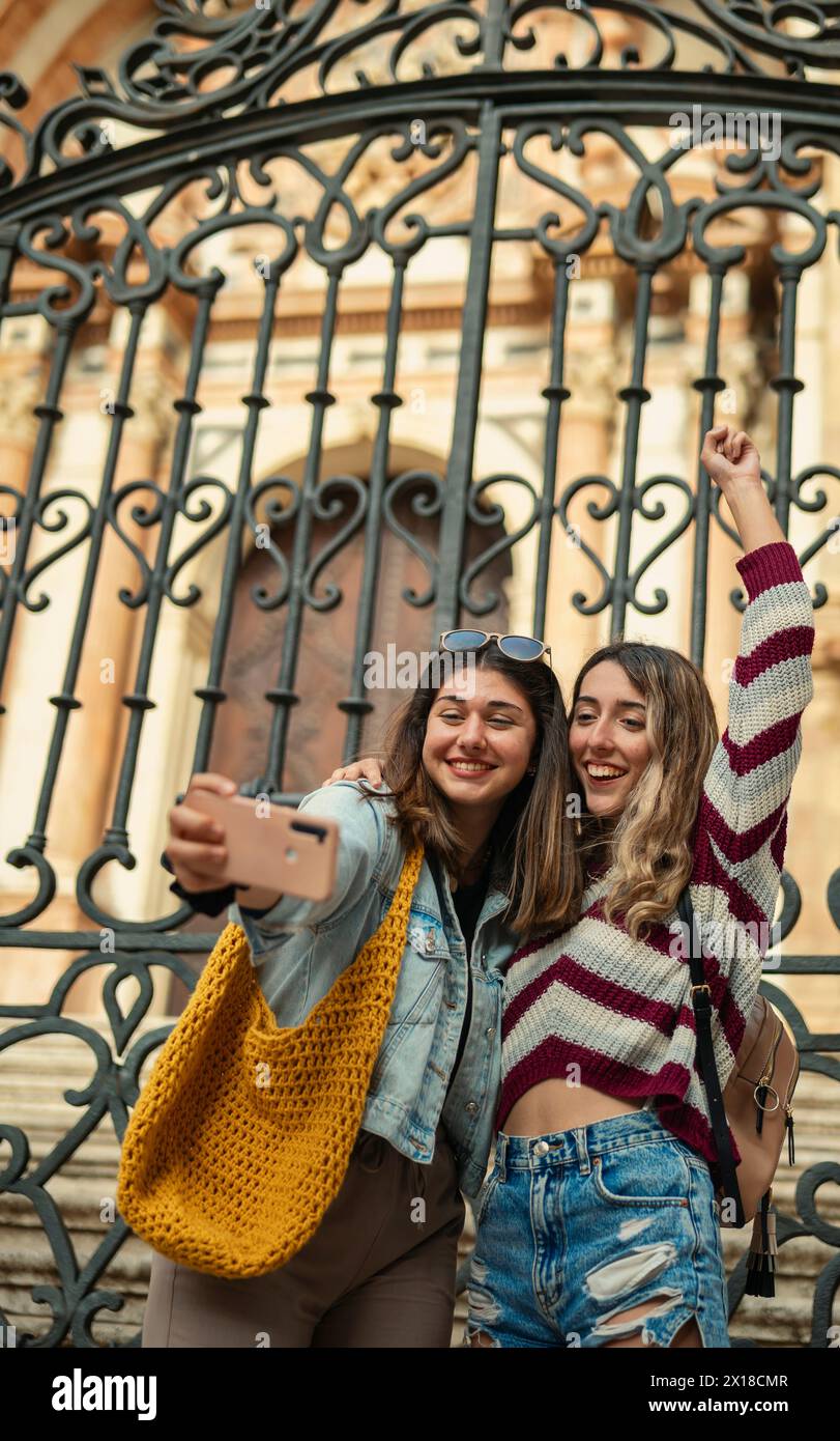 Zwei lächelnde Freunde machen ein Selfie vor der beeindruckenden Kathedrale von Malaga. Stockfoto