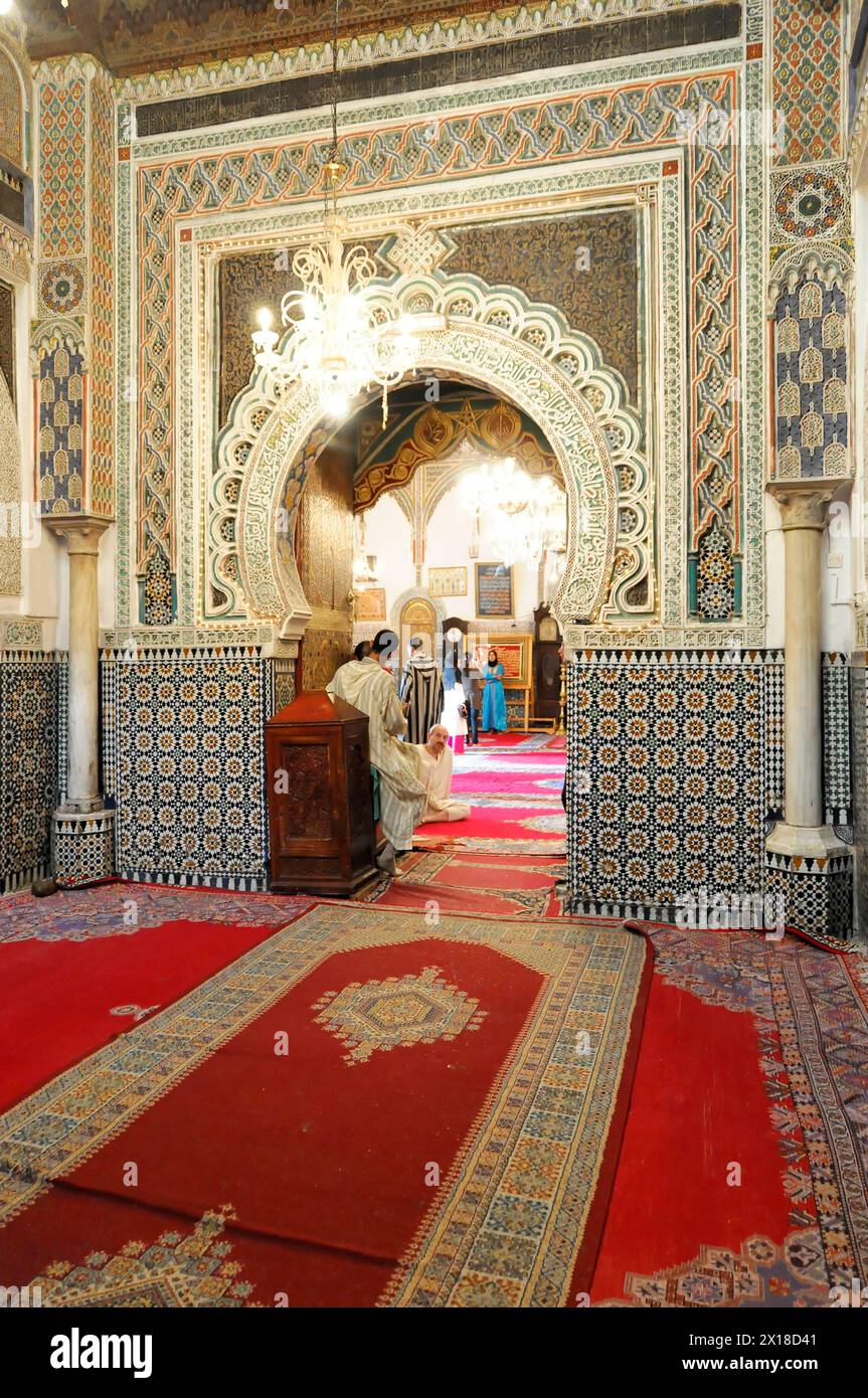 Fes, Ein prächtiges Inneres einer Moschee mit roten Teppichen und Mosaiksäulen, Nordmarokko, Marokko Stockfoto