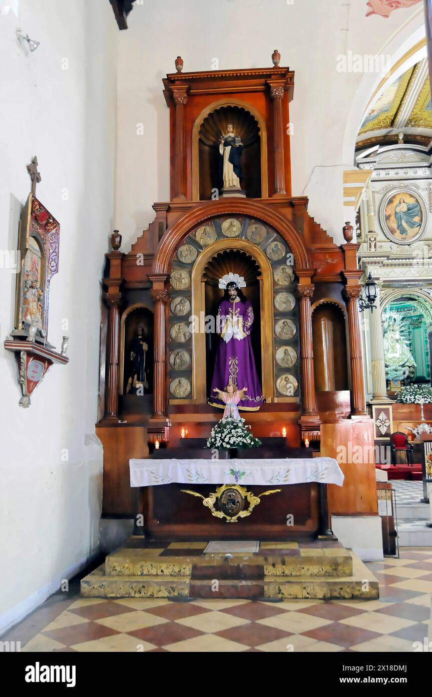 La Merced Church, erbaut um 1762, Leon, Nicaragua, Ein Kirchenaltar mit einer Figur eines heiligen in lila Gewändern, umgeben von Kerzen und Ornamenten Stockfoto