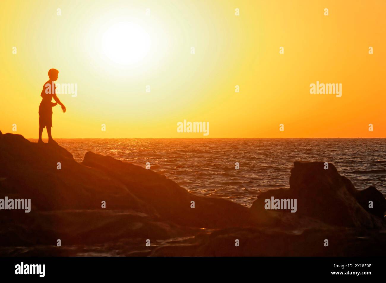 Strand in der Nähe von Poneloya, Las Penitas, Leon, Nicaragua, Silhouette einer Person auf Felsen mit Blick auf den Sonnenuntergang am Meer, Mittelamerika, Zentral Stockfoto