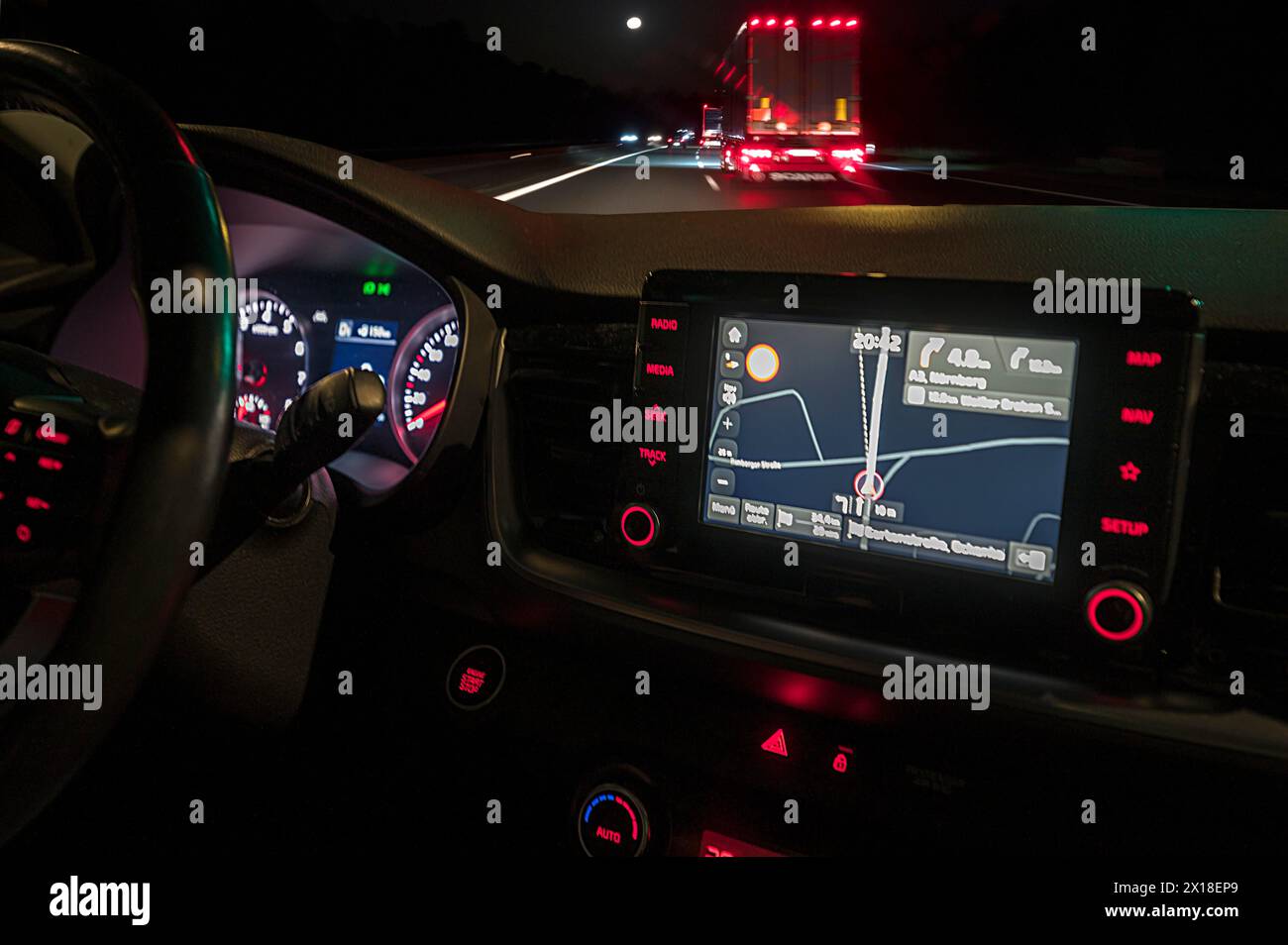 Nächtliche Straßenszene mit LKW, aus einem beleuchteten Cockpit mit Navigationsgerät eines Autos, Bayern, Deutschland Stockfoto