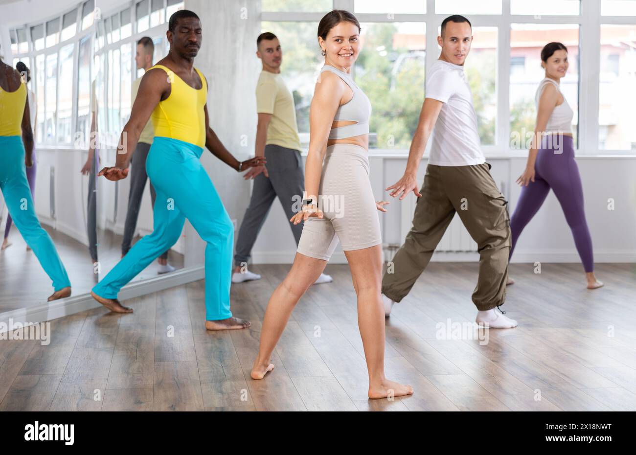 Junge weibliche Fitnesstrainerin, die die positive Zumba-Klasse anführt Stockfoto