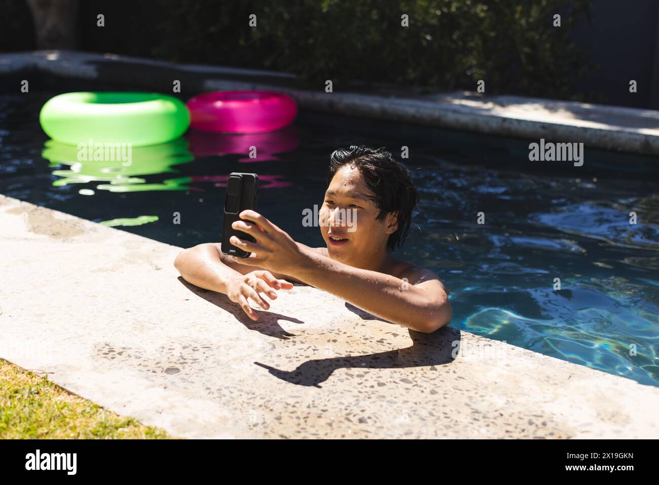 Ein asiatischer Teenager, der draußen am Pool Selfie macht, ohne Hemd Stockfoto