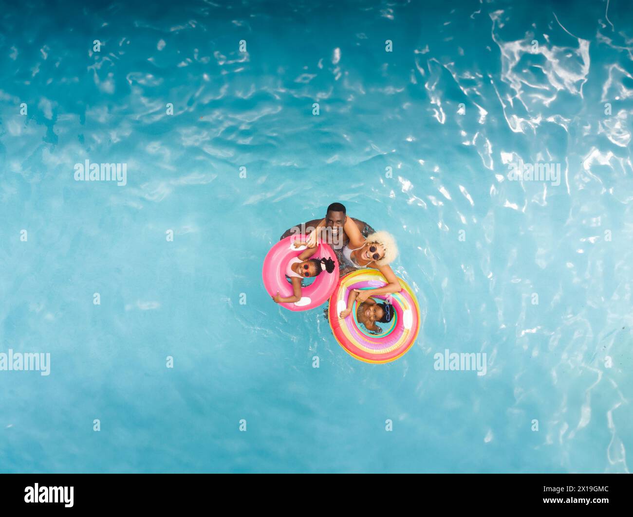 Vielfältige Familie, die zu Hause Poolzeit genießen, auf bunten Ringen schwimmen, Kopierraum Stockfoto