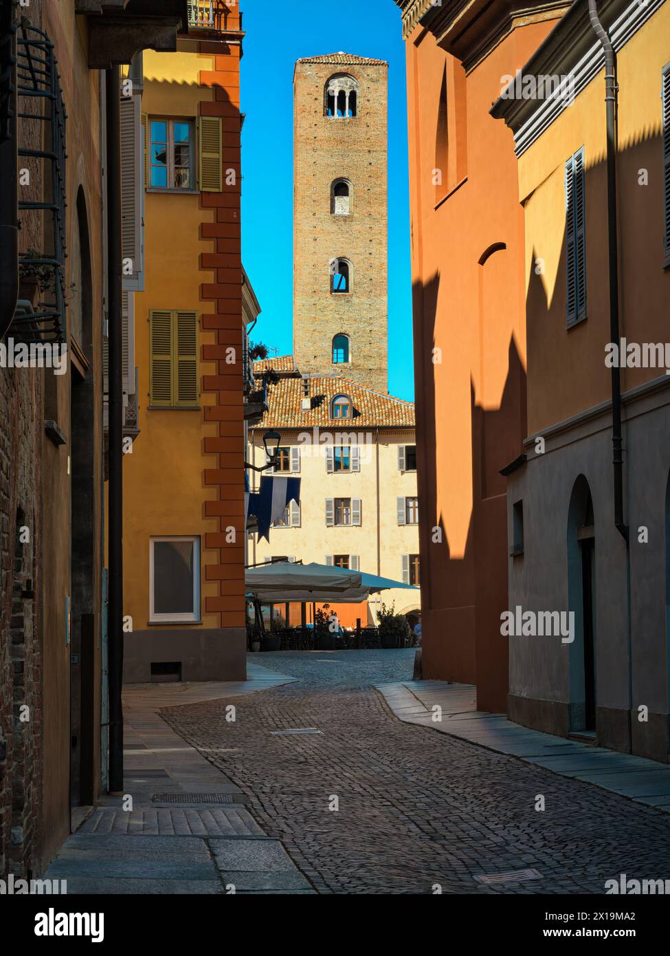 Mittelalterlicher Turm zwischen historischen Gebäuden unter blauem Himmel in der Altstadt von Alba im Piemont, Italien. Stockfoto