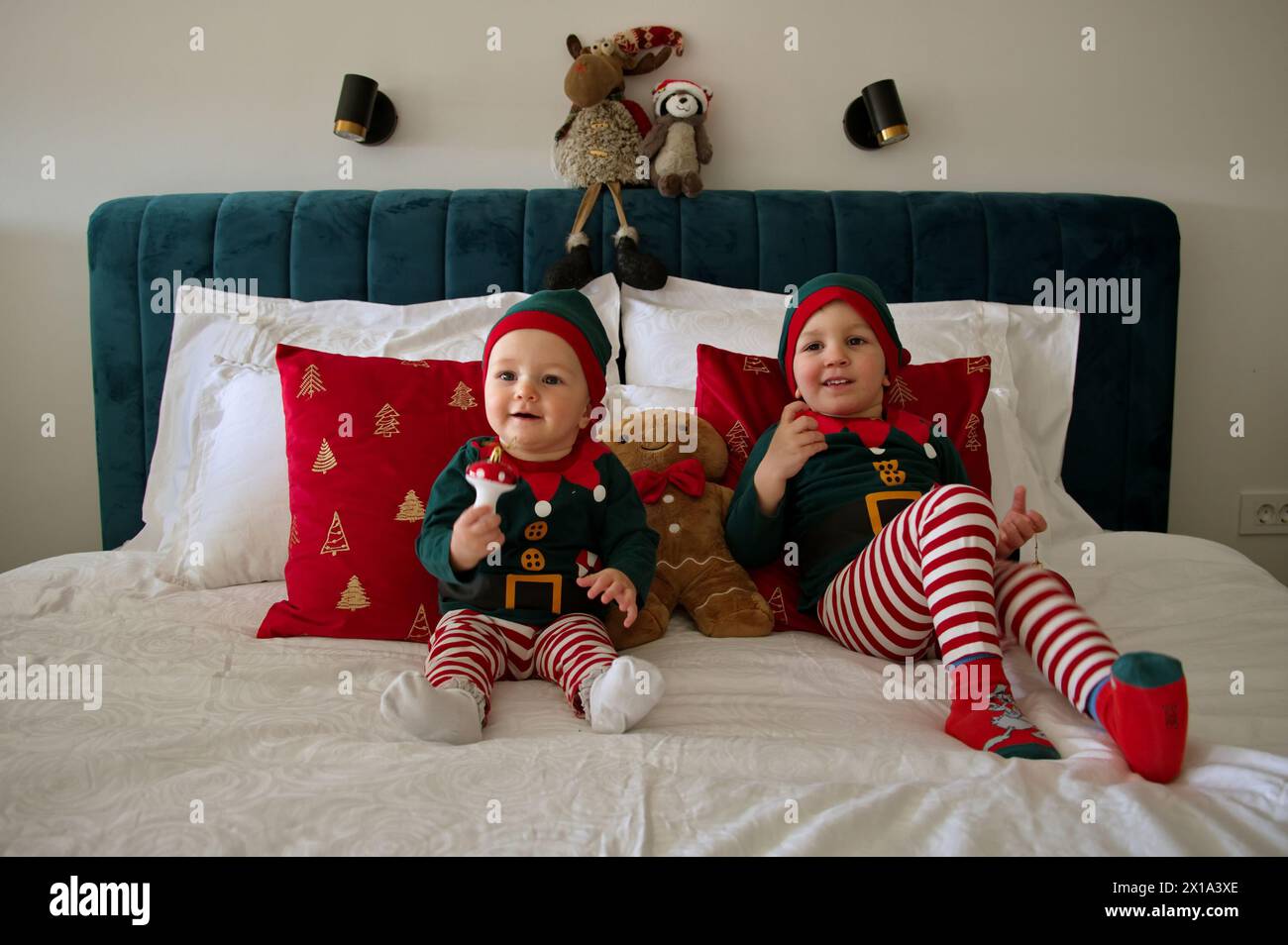 Mädchen und Kleinkind, gekleidet als Elfen, die auf einem Bett sitzen Stockfoto